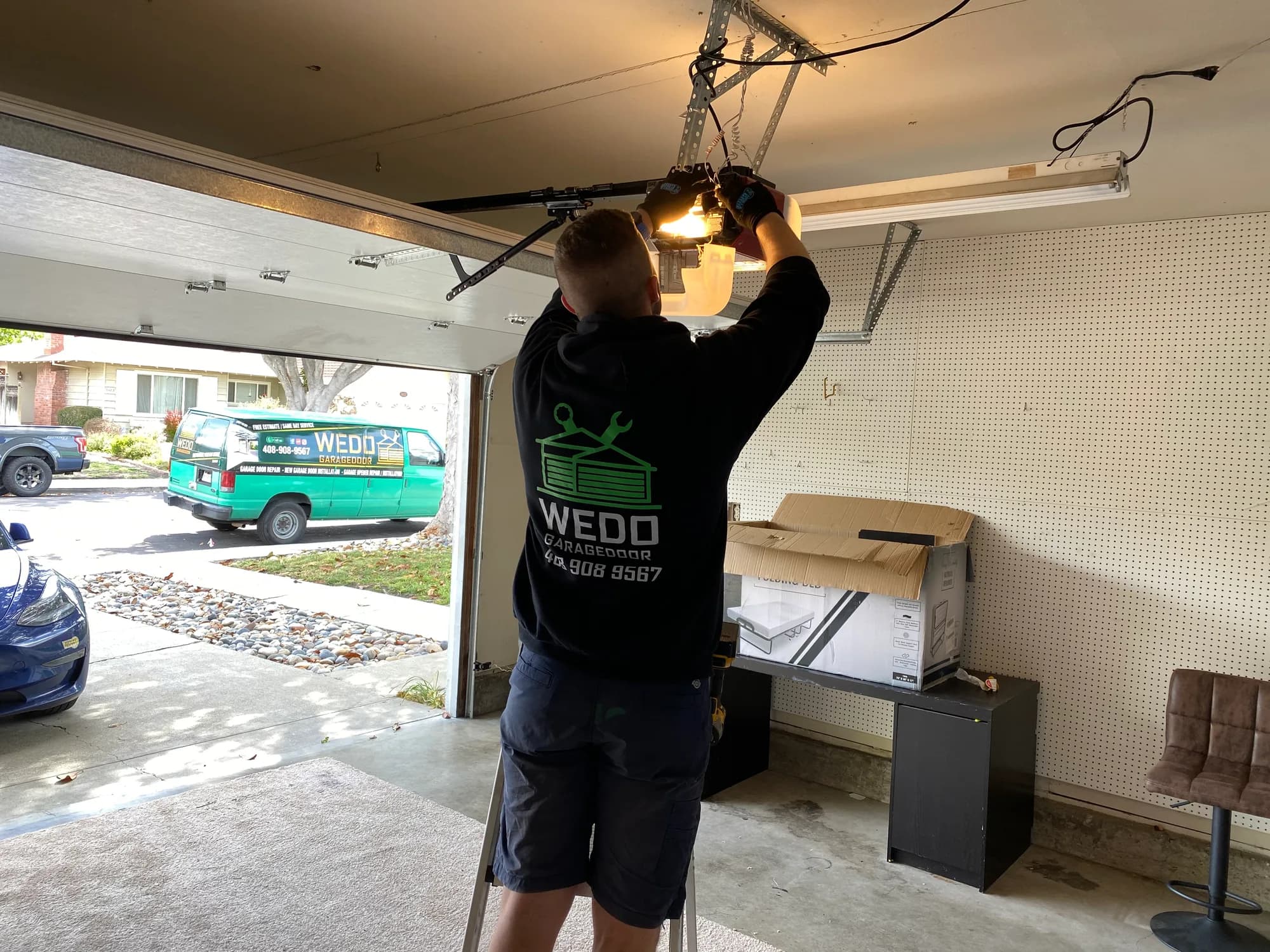 WeDo technician installing a garage door opener with the shop van in the driveway